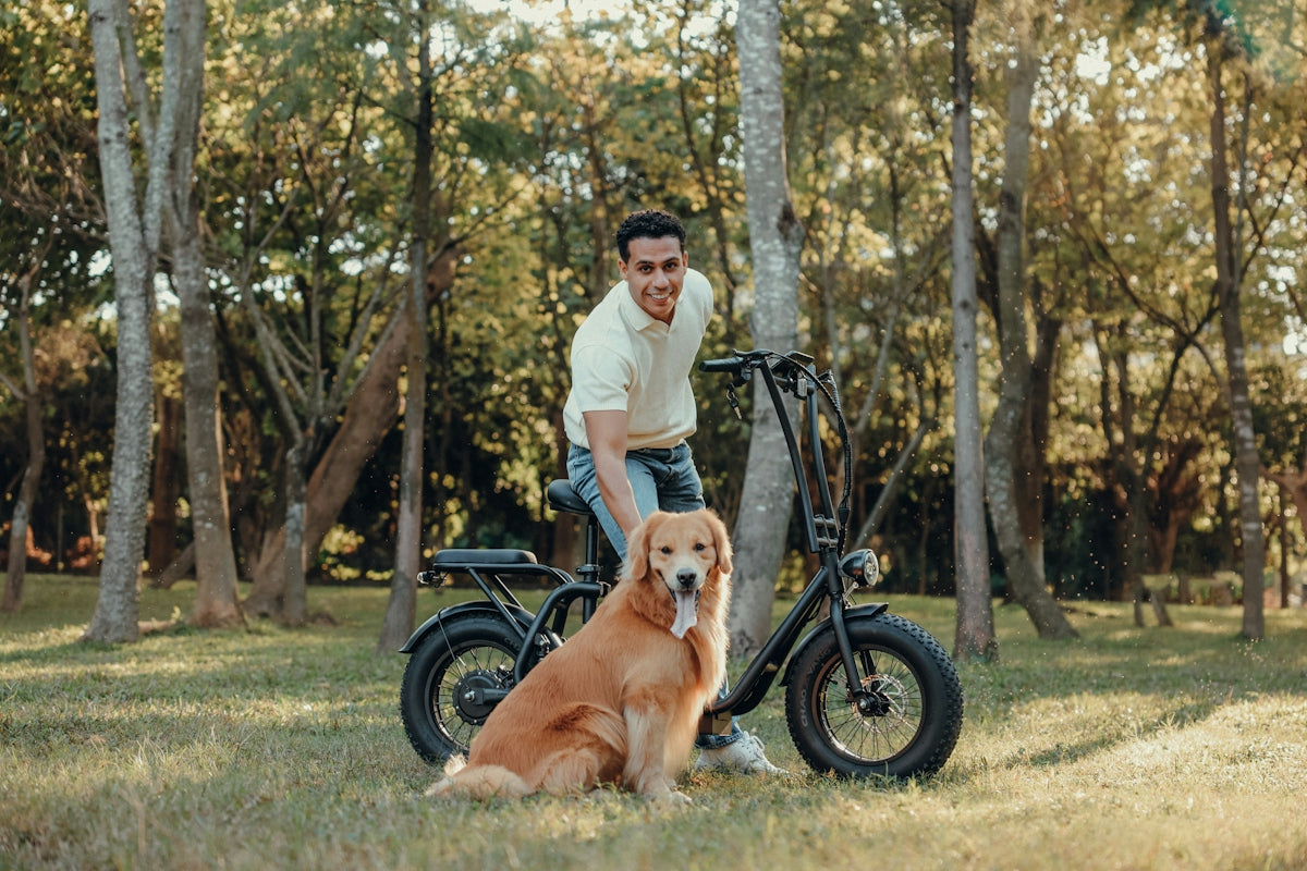 Man and dog pose by a bike in a park